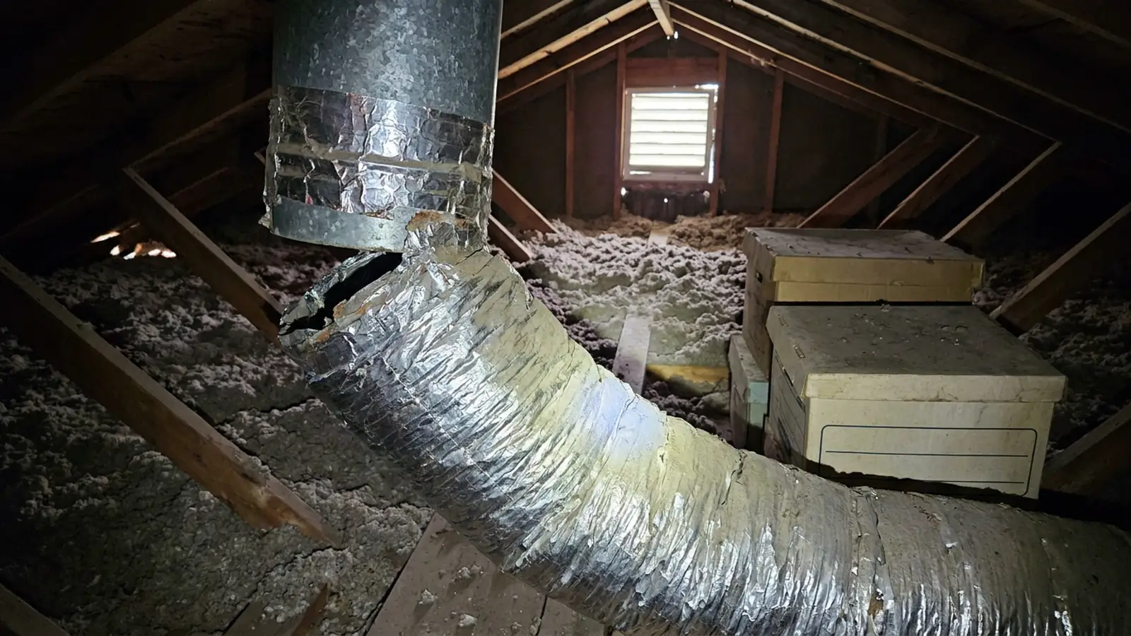 A disconnected flexible duct joint hanging loose in a hot residential attic