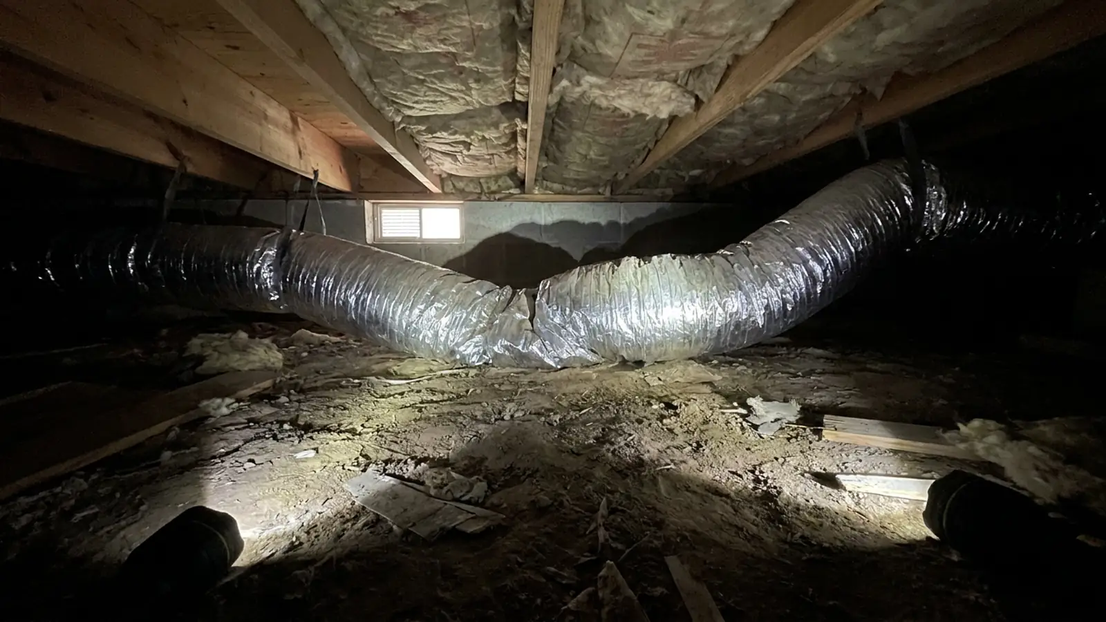 A crushed and kinked flexible duct run in a residential crawlspace