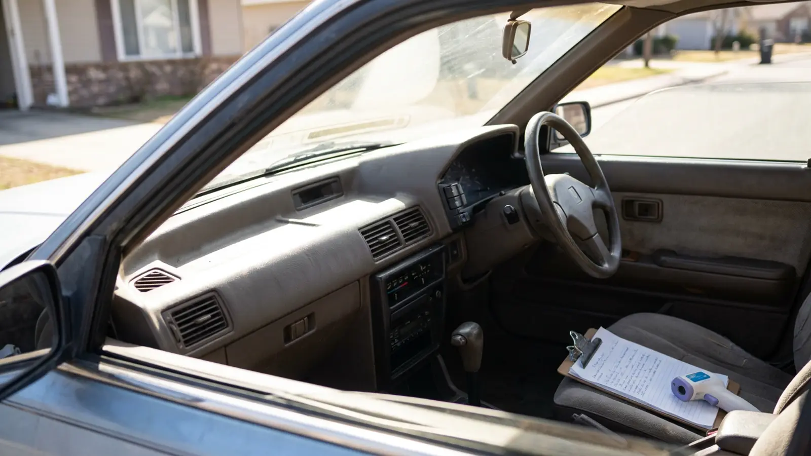 A car interior baking in summer sunlight with the driver window down and dashboard vents in view